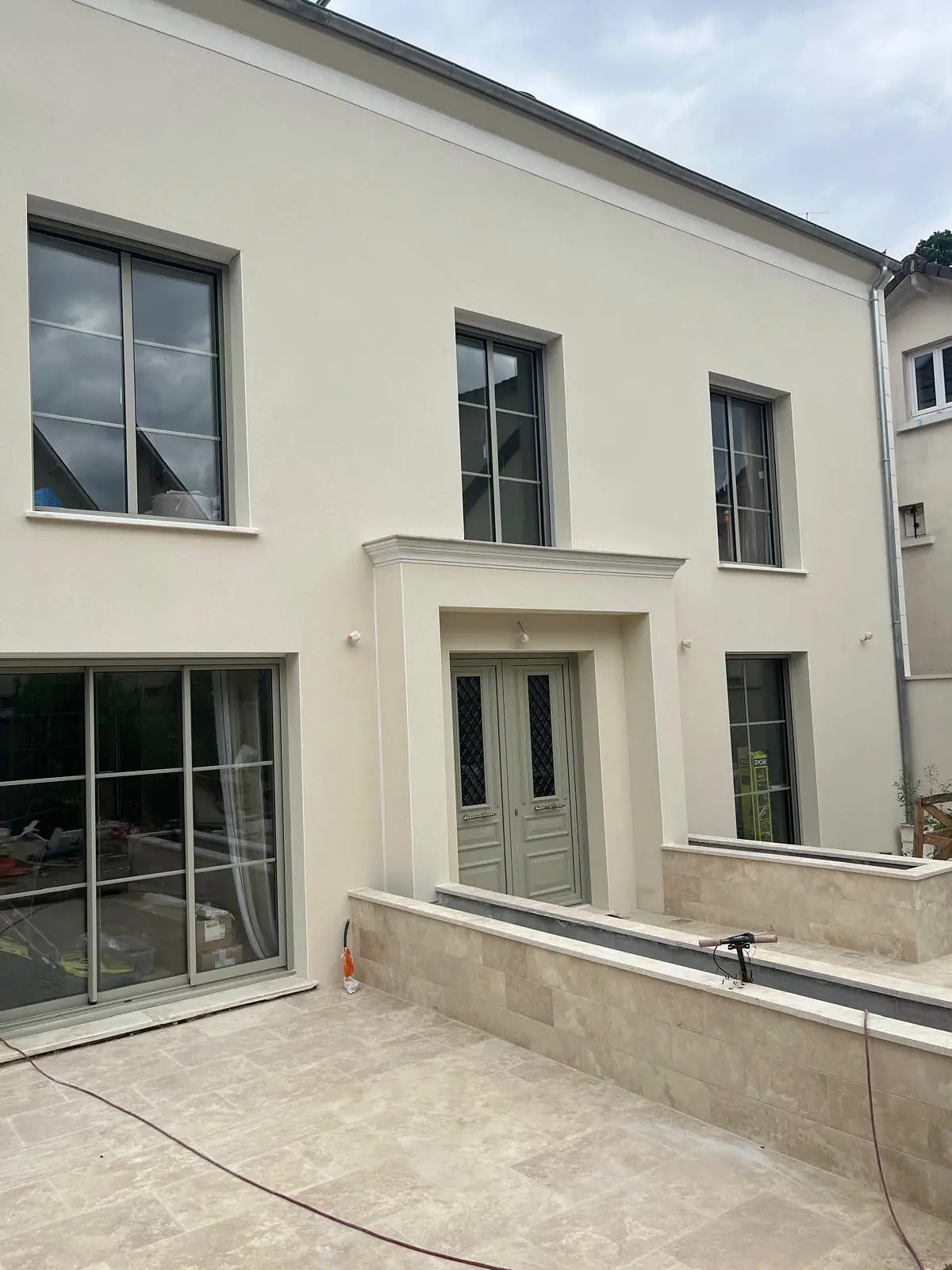 Maison neuve à façade enduite claire, encadrements de baies en saillie, en fin de chantier